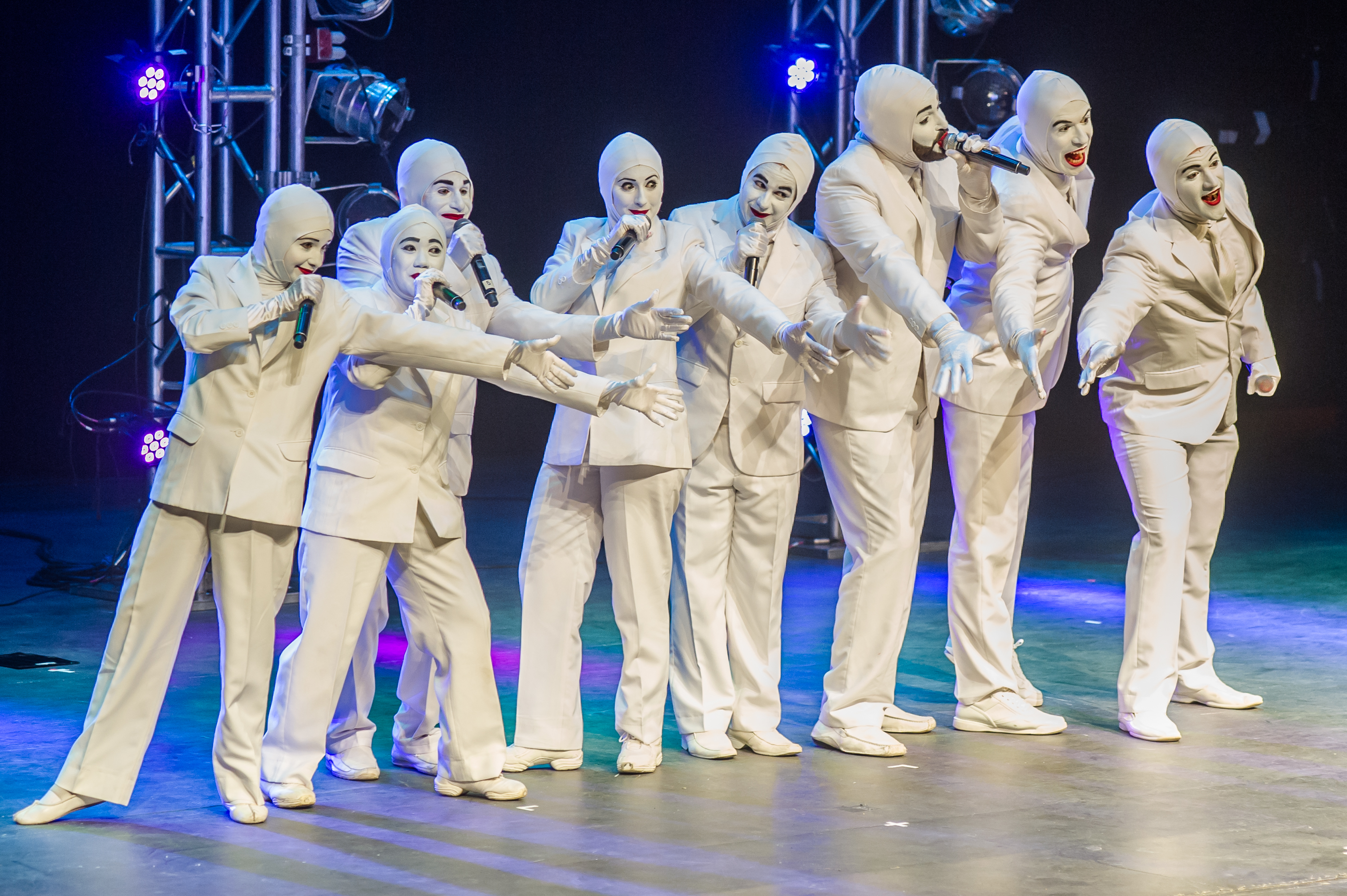 group of performers in white costumes posing on stage